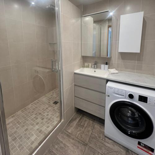 une salle de bain avec une machine à laver et un lavabo dans l'établissement Au Cœur de Disneyland, Gare & Shopping à 2 pas, à Chessy