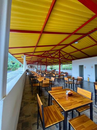 a restaurant with wooden tables and chairs and a yellow ceiling at Hotel Cafetero Valparaíso in La Vega