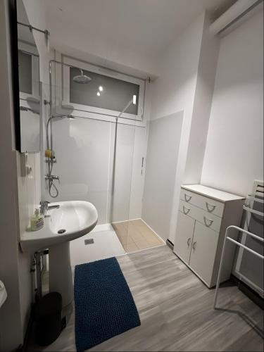 - une petite salle de bains blanche avec lavabo et miroir dans l'établissement Le Cottage Malouin, à Dunkerque