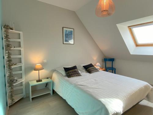 a bedroom with a white bed and a window at La Clairière in Jullouville-les-Pins