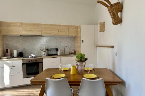 une cuisine avec une table en bois et des armoires blanches dans l'établissement Le Bohème - Center balcony and air conditioning!, à Montpellier