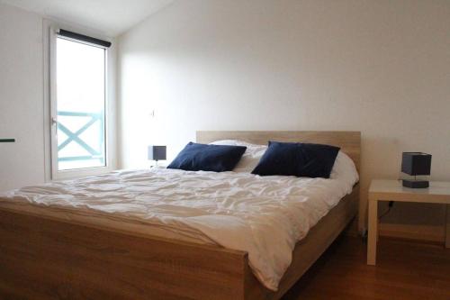 une chambre avec un lit avec des oreillers bleus et une fenêtre dans l'établissement Appt Studio mezza LA ROCHELLE - LR100-452, à La Rochelle