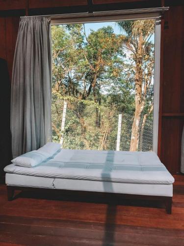 a bed in a room with a large window at Casas de Vidro - Hospedar com Propósito in Florianópolis