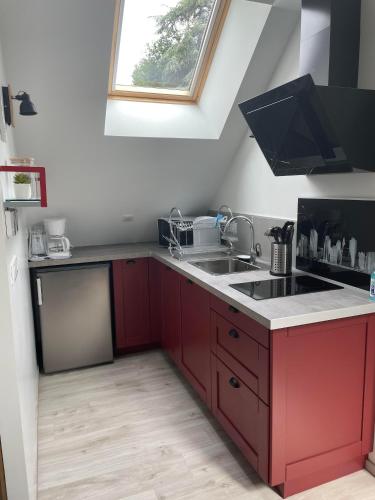 d'une cuisine avec des placards rouges, un évier et une fenêtre. dans l'établissement gîte Ludivine, à Francueil