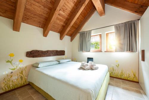 a bedroom with a large white bed with wooden ceilings at Baita Dinh - Villaggio dei Crodini in Crodo