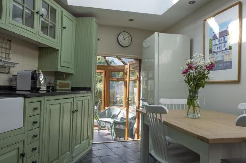 a kitchen with green cabinets and a table with flowers at Lilac Cottage by Keepers Cottages in Kingsdown