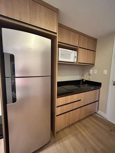 a kitchen with a stainless steel refrigerator and a microwave at Jatobá - Studio próximo à praia in Lauro de Freitas