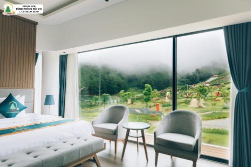 a bedroom with a bed and two chairs and a large window at Rung Thong Nui Voi Villa & Resort in Ðưc Trọng