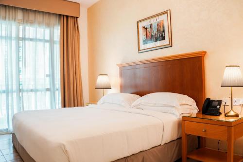 a hotel room with a bed and a telephone at Swissôtel Al Murooj Dubai in Dubai
