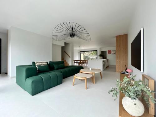 a living room with a green couch and a table at Villa Stella-plage proche Le Touquet pour 8 personnes in Cucq