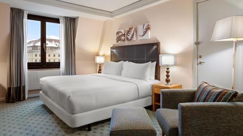 a hotel room with a bed and two chairs at Hilton Dresden an der Frauenkirche in Dresden