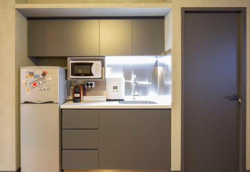 a small kitchen with a refrigerator and a microwave at Check Inn HK in Hong Kong