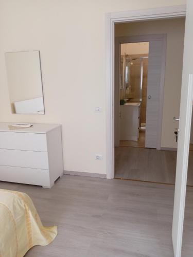 a white bedroom with a white dresser and a mirror at Affittacamere Lusitana Alloggi 2 in Foligno