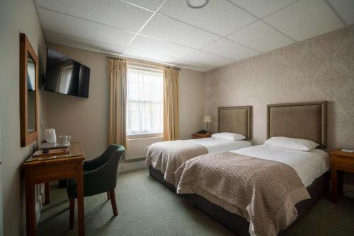 a hotel room with two beds and a desk at Stallingborough Grange Hotel in Stallingborough