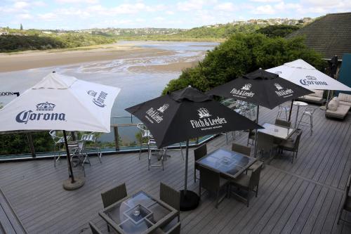 a deck with tables and umbrellas and a beach at Blue Lagoon Hotel and Conference Centre in East London