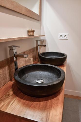 a bathroom with two black sinks on a wooden counter at Villa du Parc le Frêne in Formiguères