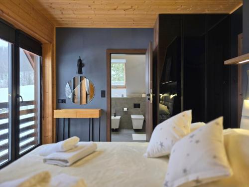 a bedroom with a bed with white pillows and a bathroom at Forest Zen Małastów dom z prywatną balią z widokami na las in Małastów
