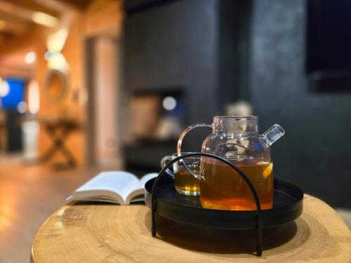 a glass jug of tea and a book on a table at Forest Zen Małastów dom z prywatną balią z widokami na las in Małastów
