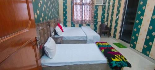 2 letti in una camera con carta da parati verde di OYO 82076 Hotel Balaji Palace a Ayodhya