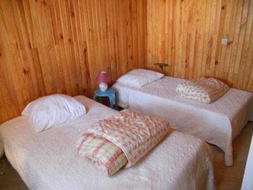 deux lits dans une chambre aux murs en bois dans l'établissement villa soulacaise proche du marche, à Soulac-sur-Mer