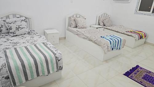 a bedroom with two beds and a tiled floor at Welcome Three 5km far from Masjid Nabawi in Al Madinah