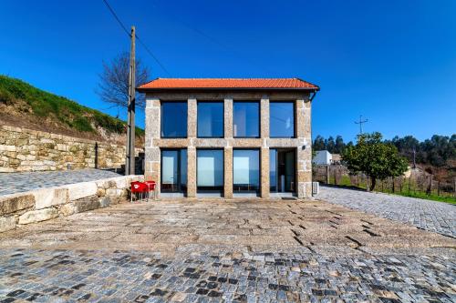a building with glass windows on a stone road at Quinta de Casal do Bairro - Casa do Alpendre in Guimarães