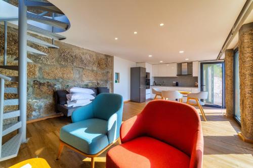 a living room with two chairs and a staircase at Quinta de Casal do Bairro - Casa do Alpendre in Guimarães