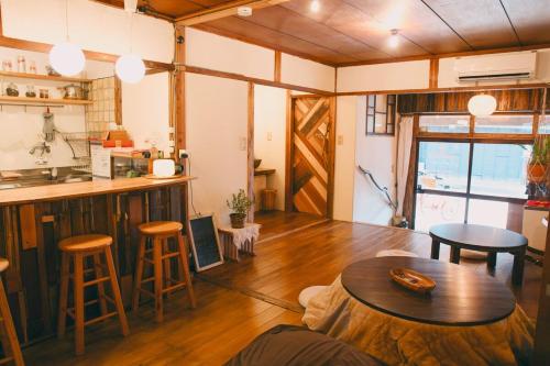 a living room with a table and a kitchen at 宿たぬきのねどこ GUESTHOUSE TANUKI in Tokoname