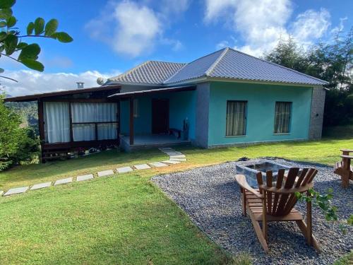 a blue house with a chair in the yard at Casa Bella Collina in Venda Nova do Imigrante