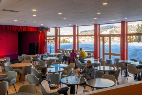 people sitting at tables in a room with windows at Belambra Clubs Les Saisies - Les Embrunes - Ski pass included in Villard-sur-Doron