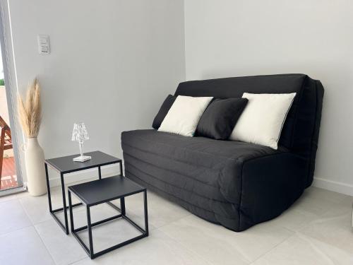 - un canapé noir avec deux tables dans le salon dans l'établissement La Grande Motte - centre ville - 2 min de la plage, à La Grande Motte