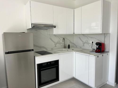 La cuisine blanche est équipée d'un réfrigérateur et d'un évier. dans l'établissement La Grande Motte - centre ville - 2 min de la plage, à La Grande Motte