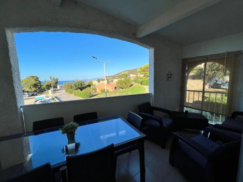 - un salon avec une table, des chaises et une grande fenêtre dans l'établissement Marine de Sant'Ambroggio, à Lumio