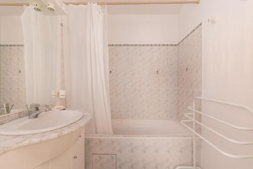 La salle de bains blanche est pourvue d'un lavabo et d'une baignoire. dans l'établissement Esquiròu Varois - Maison avec piscine, à Moissac-Bellevue