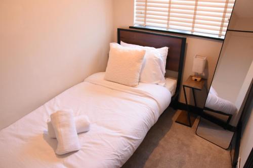 a small bedroom with a bed with white sheets and pillows at Eden Escape - Bham Airport, NEC, HS2, JLR, Park Access in Sheldon