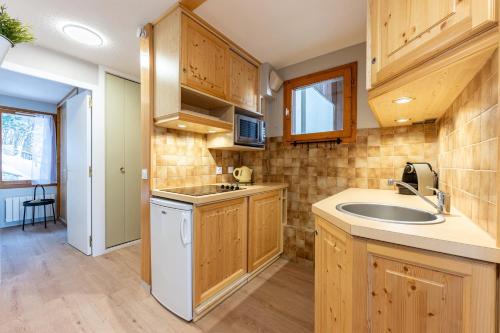 une cuisine avec des armoires en bois et un évier dans l'établissement Les Verdons - Chalet Bellevue Domaine La Plagne, à Mâcot La Plagne