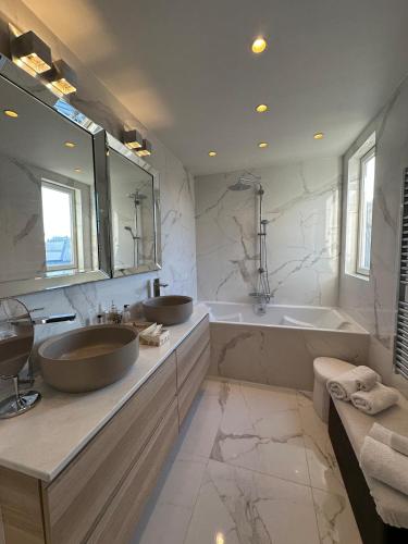 une salle de bain avec deux lavabos, une baignoire et un miroir dans l'établissement Beautiful apartment terrace Invalides and fireplace, à Paris