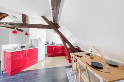 a kitchen with red cabinets and a wooden table at La Nuit du Drouais in Dreux