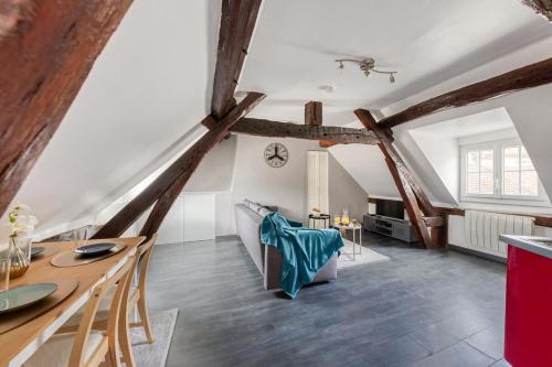 an attic room with wooden beams and a table and chairs at La Nuit du Drouais in Dreux
