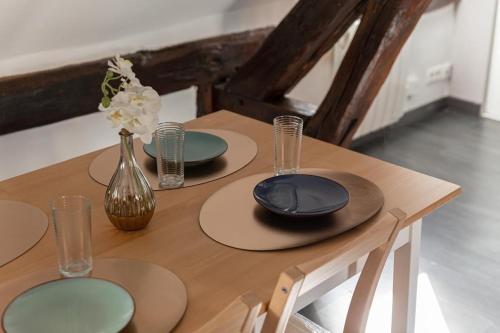 a wooden table with three plates and a vase with flowers at La Nuit du Drouais in Dreux