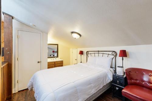 a bedroom with a white bed and a red chair at Redwood Commons B12 in Angel Fire
