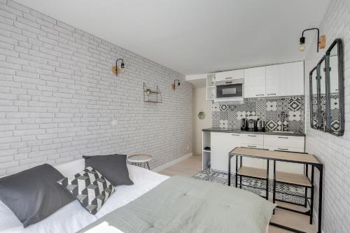 - une chambre avec un lit et un mur en briques blanches dans l'établissement Cosy Studio in center of Paris, à Paris