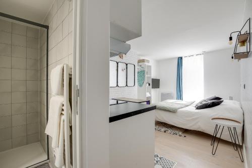 La salle de bains blanche est pourvue d'un lit et d'une douche en verre. dans l'établissement Cosy Studio in center of Paris, à Paris