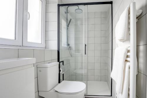 une salle de bain blanche avec toilettes et douche dans l'établissement Cosy Studio in center of Paris, à Paris