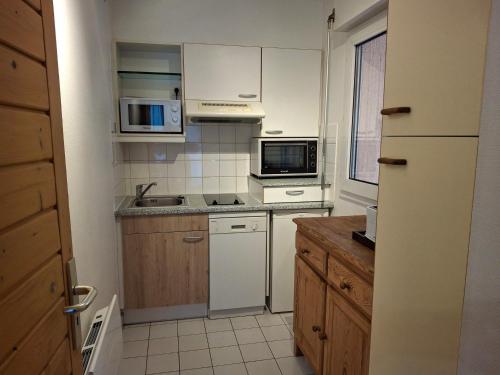 une petite cuisine avec des armoires blanches et un micro-ondes dans l'établissement Studio central à Brides-Les-Bains avec parking, wifi, animaux admis - FR-1-512-281, à Brides-les-Bains