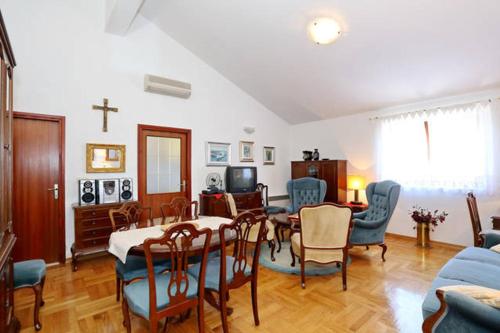ein Wohnzimmer mit einem Tisch, Stühlen und einem Kreuz in der Unterkunft Apartment Sara in Pirovac