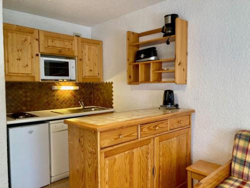 Elle comprend une petite cuisine avec des placards en bois et un évier. dans l'établissement Studio confortable, pied de pistes au cœur des Deux Alpes, animaux admis - FR-1-811-26, à Les Deux Alpes