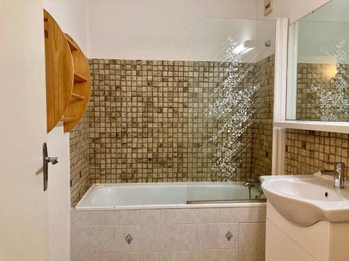 une salle de bain avec une baignoire et un lavabo dans l'établissement Studio confortable, pied de pistes au cœur des Deux Alpes, animaux admis - FR-1-811-26, à Les Deux Alpes