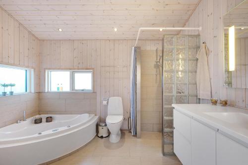 une salle de bain avec une baignoire, des toilettes et un lavabo dans l'établissement Beautiful And Well-Designed Holiday Home With Sea View, Spacious Terraces And Spa Just 200 Metres From The Child-Friendly Femmøller Beach And Close, à Ebeltoft