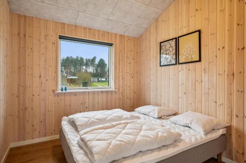 ein Schlafzimmer mit einem Bett in einer Holzwand in der Unterkunft Beautiful And Modern 8-Person Holiday Home With Spacious Terraces And Quality Interiors Located In Peaceful Fuglslev Close To Forest, Nature And in Ebeltoft